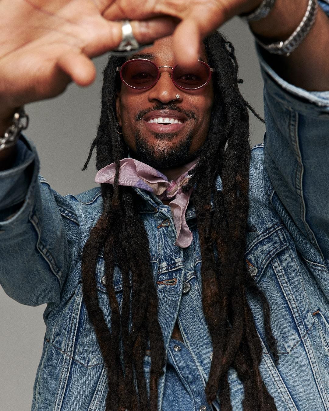 Greg Banks smiling in double denim and rose-tinted sunglasses